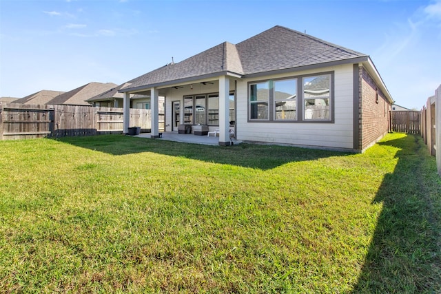 back of property with ceiling fan, a patio, and a lawn