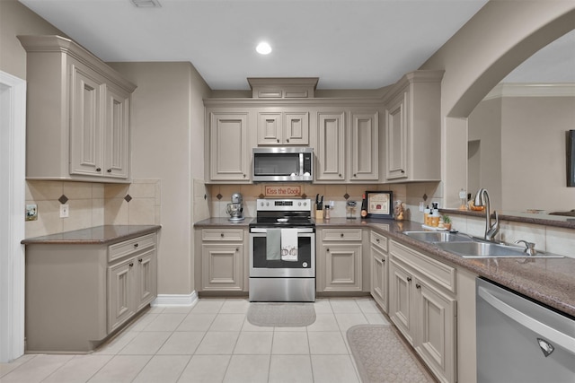 kitchen with appliances with stainless steel finishes, decorative backsplash, sink, and light tile patterned floors