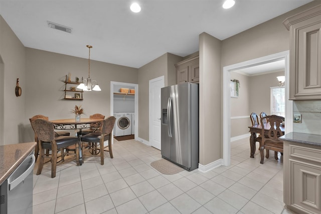 kitchen featuring dark stone countertops, a chandelier, appliances with stainless steel finishes, hanging light fixtures, and washer / dryer