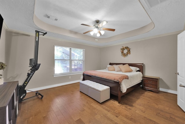 bedroom featuring hardwood / wood-style flooring, a raised ceiling, ceiling fan, and a textured ceiling