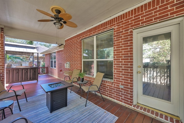 deck featuring ceiling fan and a fire pit