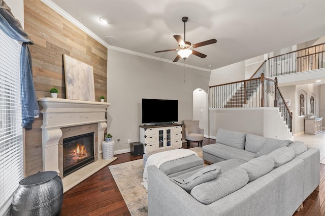 living room featuring hardwood / wood-style flooring, ceiling fan, crown molding, and wooden walls