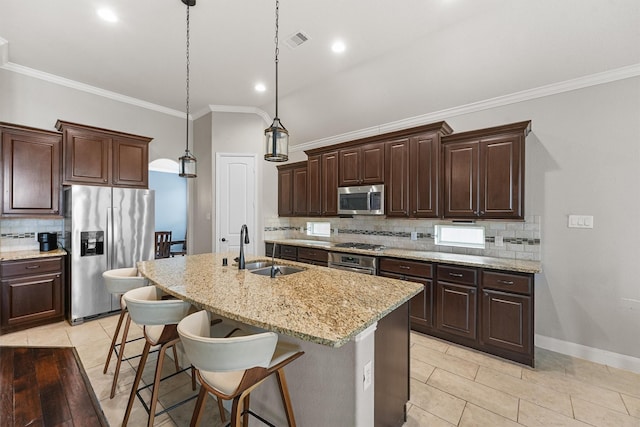 kitchen with appliances with stainless steel finishes, an island with sink, a kitchen bar, sink, and decorative light fixtures