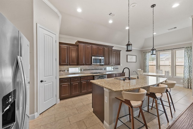 kitchen featuring sink, decorative light fixtures, light stone counters, a center island with sink, and appliances with stainless steel finishes