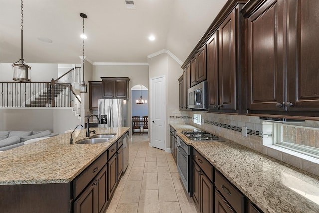 kitchen featuring a kitchen island with sink, appliances with stainless steel finishes, hanging light fixtures, sink, and dark brown cabinets