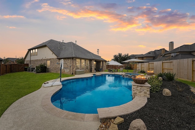 pool at dusk with an in ground hot tub, a patio area, and a lawn