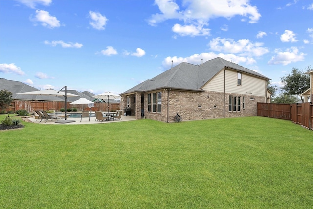 rear view of house with a lawn, a swimming pool, and a patio area