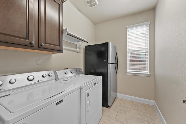 clothes washing area featuring light tile patterned flooring, cabinets, and washing machine and clothes dryer