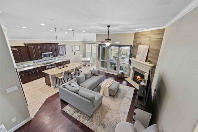 living room featuring a premium fireplace, ceiling fan, and crown molding