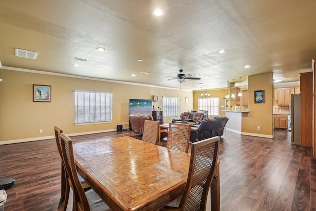 dining area with ceiling fan with notable chandelier, a textured ceiling, crown molding, and dark hardwood / wood-style flooring