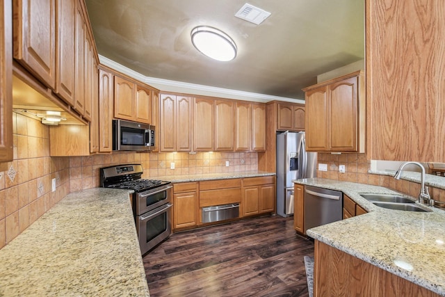 kitchen featuring sink, appliances with stainless steel finishes, light stone counters, ornamental molding, and dark wood-type flooring