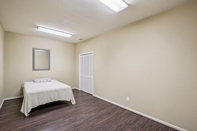 bedroom featuring dark hardwood / wood-style flooring and a textured ceiling