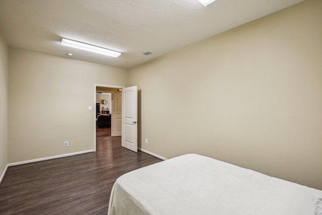 bedroom with a textured ceiling and dark hardwood / wood-style floors