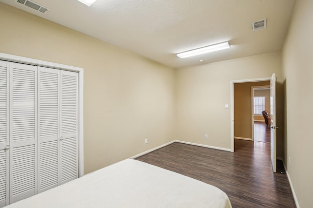 bedroom featuring a textured ceiling, dark hardwood / wood-style flooring, and a closet