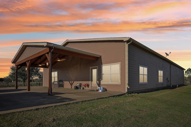 back house at dusk featuring a patio area and a yard