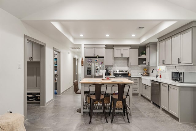 kitchen with appliances with stainless steel finishes, a raised ceiling, gray cabinets, and sink