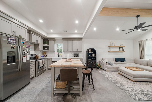 kitchen with a center island, a kitchen breakfast bar, tasteful backsplash, gray cabinets, and appliances with stainless steel finishes