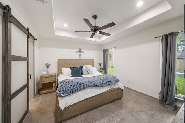 bedroom featuring a raised ceiling, ceiling fan, and a barn door