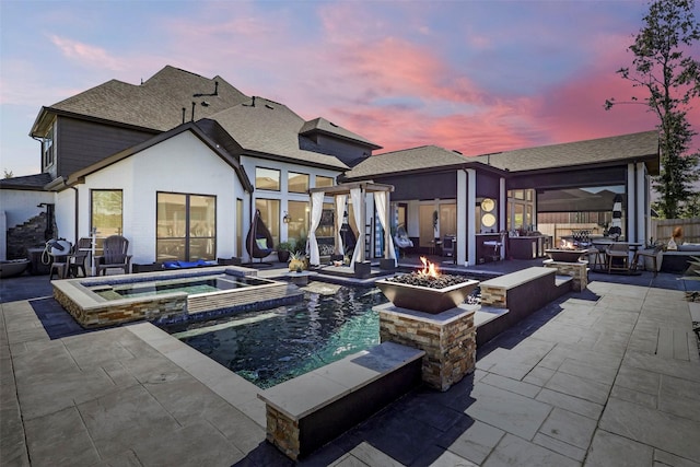 pool at dusk featuring an outdoor fire pit, an in ground hot tub, and a patio