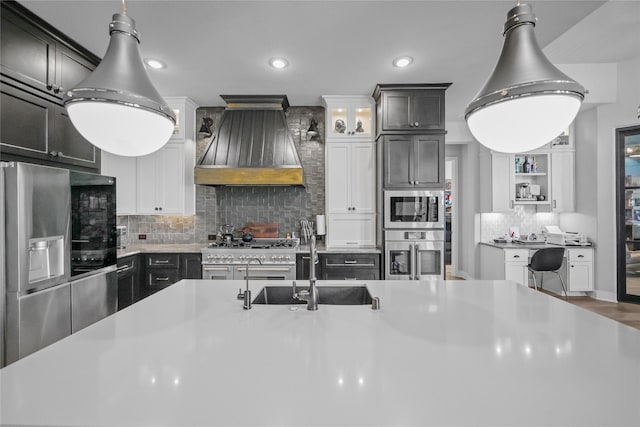 kitchen featuring appliances with stainless steel finishes, pendant lighting, tasteful backsplash, and custom range hood