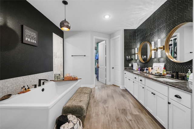 bathroom featuring tasteful backsplash, hardwood / wood-style floors, a tub, and vanity