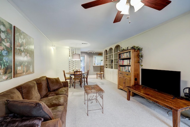 living room featuring light colored carpet, ceiling fan, and ornamental molding