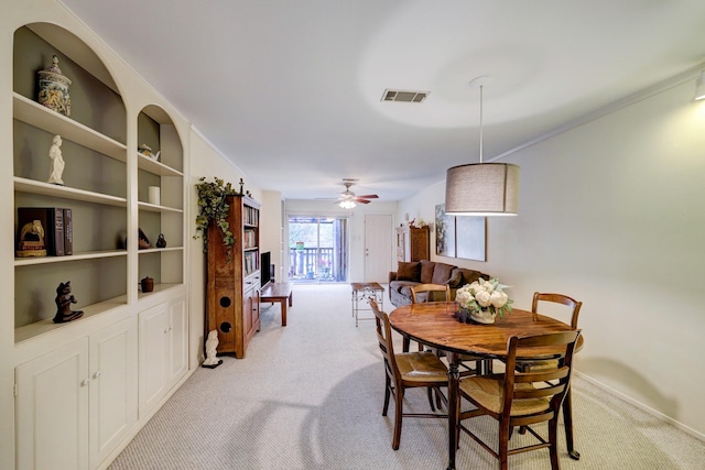 dining space featuring built in shelves, light colored carpet, and ceiling fan