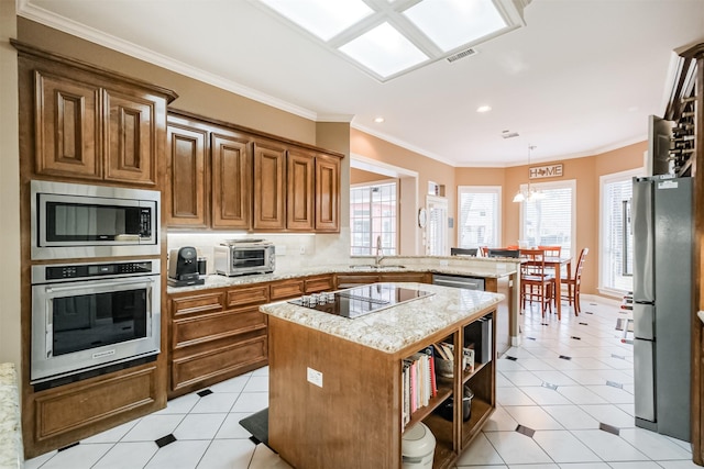 kitchen featuring sink, appliances with stainless steel finishes, hanging light fixtures, a kitchen island, and kitchen peninsula