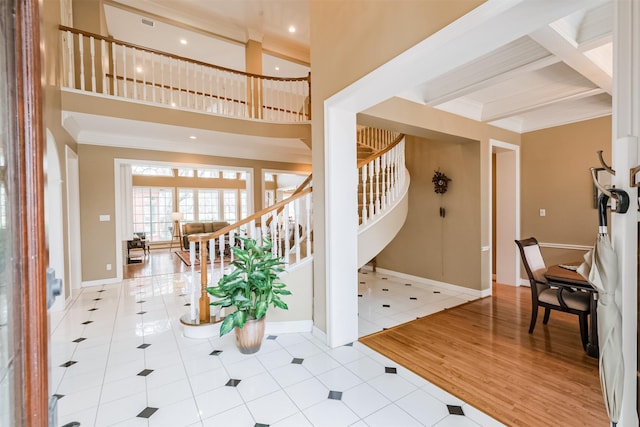 tiled foyer with a towering ceiling, ornamental molding, and beam ceiling