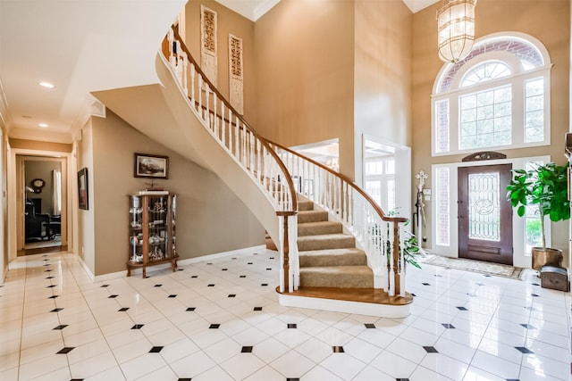 foyer entrance with an inviting chandelier, crown molding, a high ceiling, and light tile patterned flooring