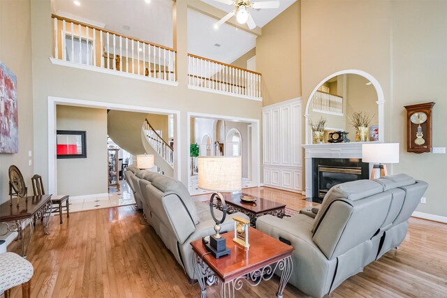 living room featuring a towering ceiling, light hardwood / wood-style flooring, and ceiling fan