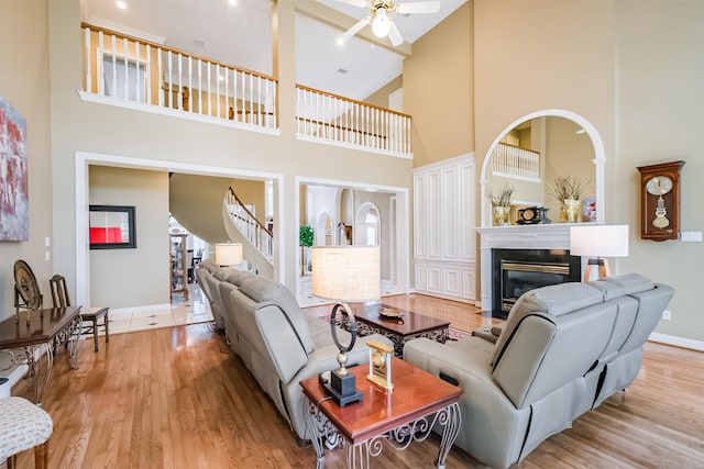 living area featuring stairs, ceiling fan, wood finished floors, and a fireplace with flush hearth