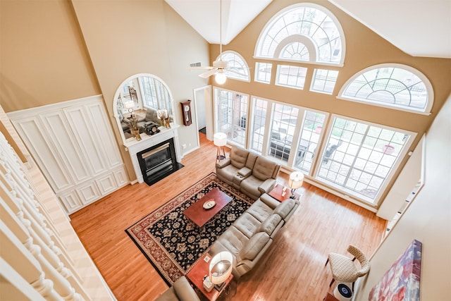 living room with ceiling fan, a healthy amount of sunlight, wood-type flooring, and high vaulted ceiling