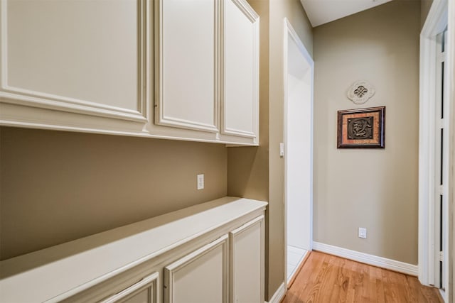 hallway featuring light wood-style flooring and baseboards