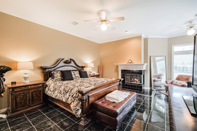 bedroom with ceiling fan, ornamental molding, and a tile fireplace