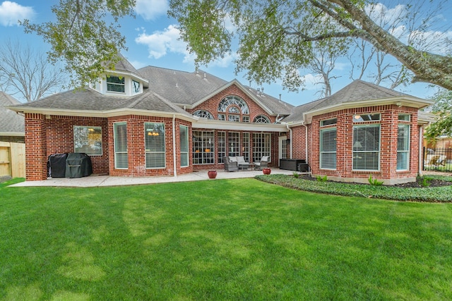 back of house featuring roof with shingles, brick siding, a lawn, a patio area, and fence