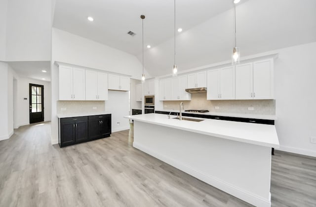 kitchen with decorative light fixtures, white cabinets, high vaulted ceiling, and a kitchen island with sink