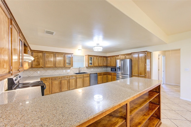 kitchen featuring light stone counters, light tile patterned flooring, kitchen peninsula, backsplash, and appliances with stainless steel finishes