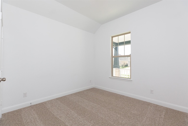 carpeted empty room with vaulted ceiling and baseboards