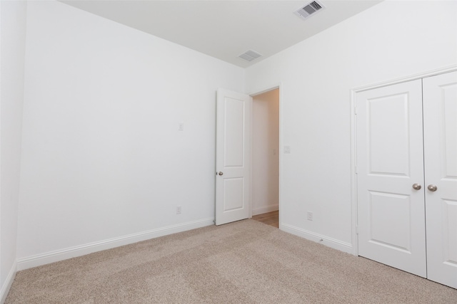 unfurnished bedroom featuring baseboards, a closet, visible vents, and carpet flooring