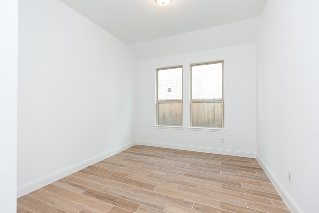 unfurnished room with wood tiled floor, vaulted ceiling, and baseboards