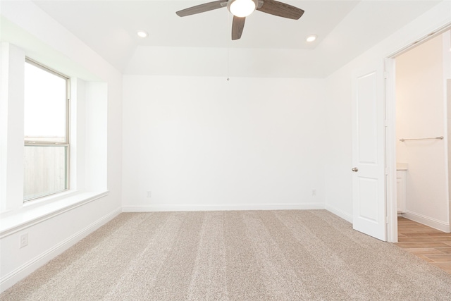 spare room featuring recessed lighting, a raised ceiling, light carpet, and baseboards