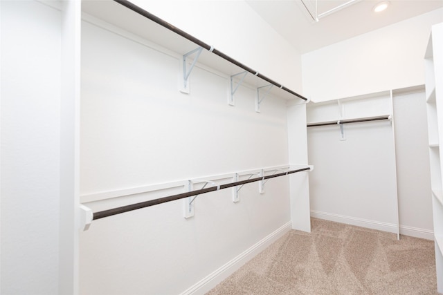 walk in closet featuring attic access and light colored carpet