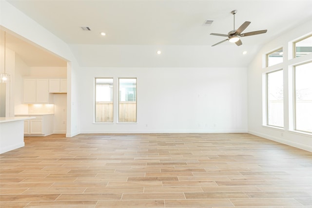 unfurnished living room featuring a wealth of natural light, visible vents, vaulted ceiling, and light wood-style flooring