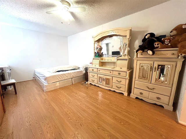 bedroom with a textured ceiling, ceiling fan, and light wood-type flooring