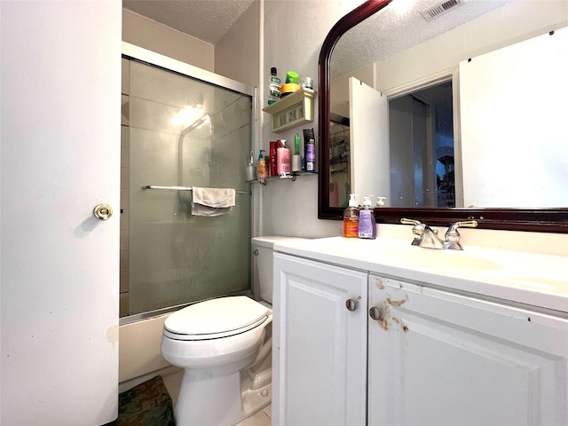 full bathroom featuring vanity, toilet, combined bath / shower with glass door, and a textured ceiling