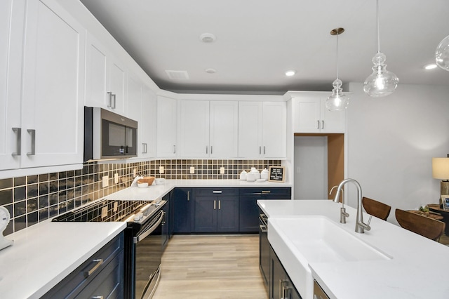 kitchen with sink, decorative light fixtures, white cabinetry, blue cabinetry, and appliances with stainless steel finishes