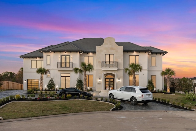 view of front of house with a balcony, french doors, and a yard