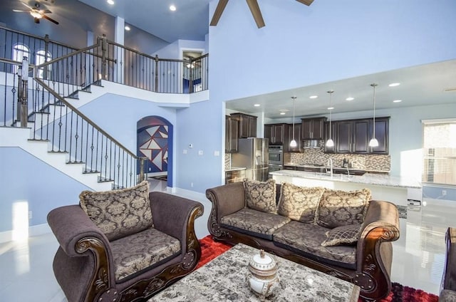 living room featuring ceiling fan and a towering ceiling