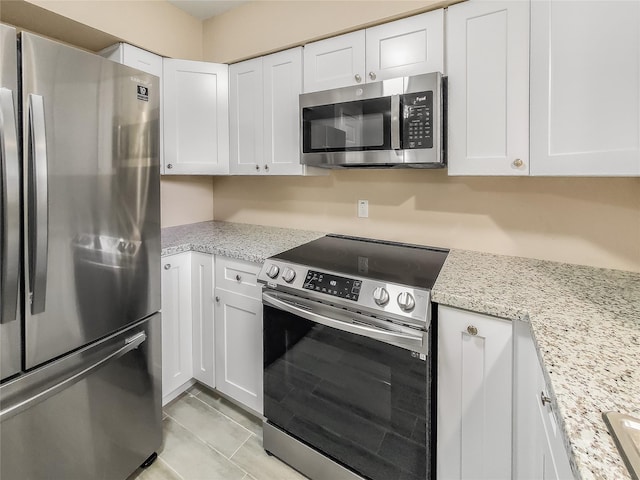 kitchen with light stone counters, stainless steel appliances, and white cabinetry